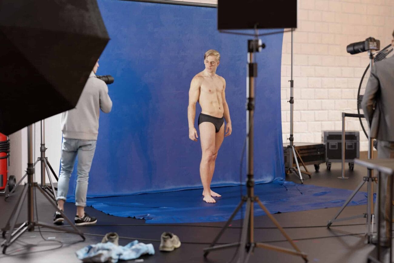 High-quality 3D male model in underwear standing in a professional photo shoot studio with blue screen backdrop.