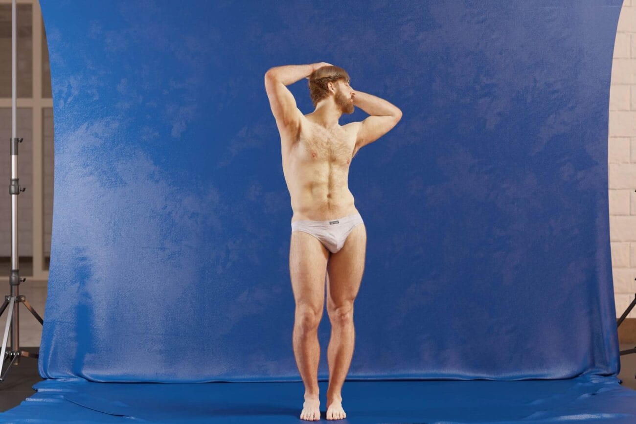 3D male model standing in underwear with studio blue backdrop, showcasing realistic anatomy, perfect for Daz3D assets and 3D rendering projects.