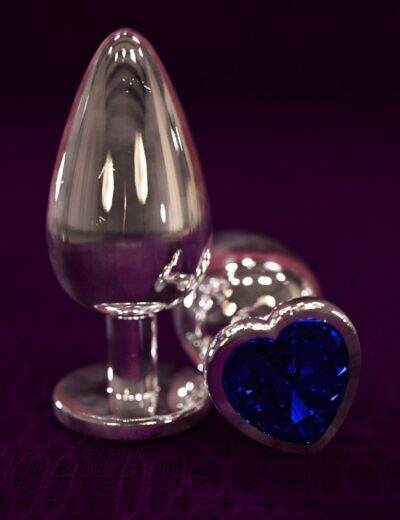 Shiny silver love heart and bullet-shaped objects with a dark purple background, showcasing high-quality 3D renderings of erotic adult toys and jewelry.